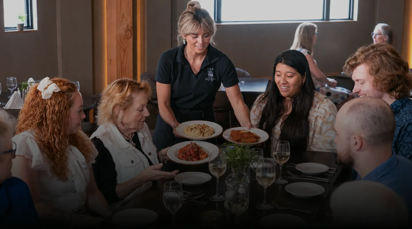 Guests sharing pasta and conversation around a table in Joey's dining room