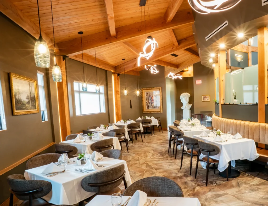Joey's dining room with tables set in white linen under wood beams and pendant lights