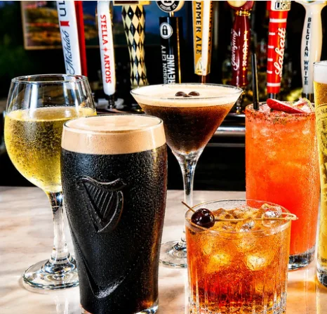 A glass of white wine, a stout, an espresso martini and a cocktail at the bar