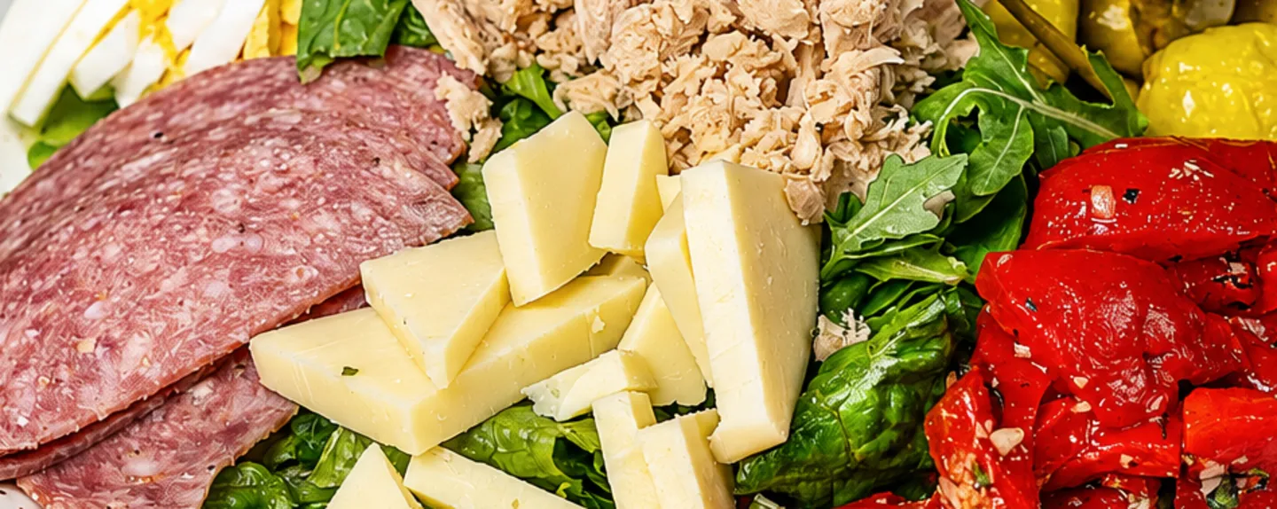 An antipasto platter of salami, tuna, roasted red peppers and greens