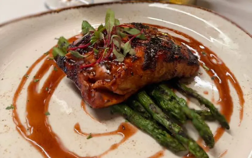 A glazed steak with asparagus on a white plate