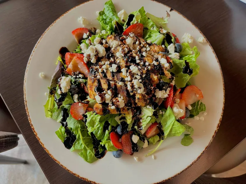 A salad with grilled chicken, tomatoes and balsamic drizzle