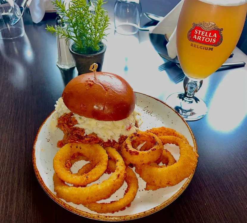 A burger with onion rings and a glass of beer