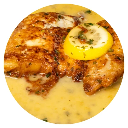 A golden cutlet in lemon butter sauce with a slice of lemon