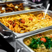 Catering trays of penne pasta and greens