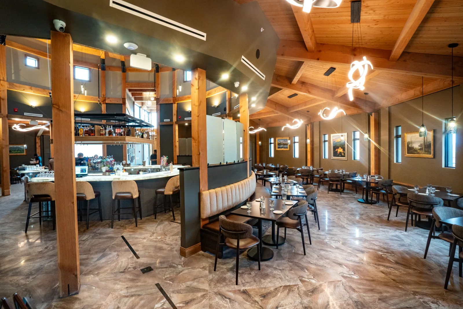 Joey's dining room with warm wood beams, a central bar, and set tables
